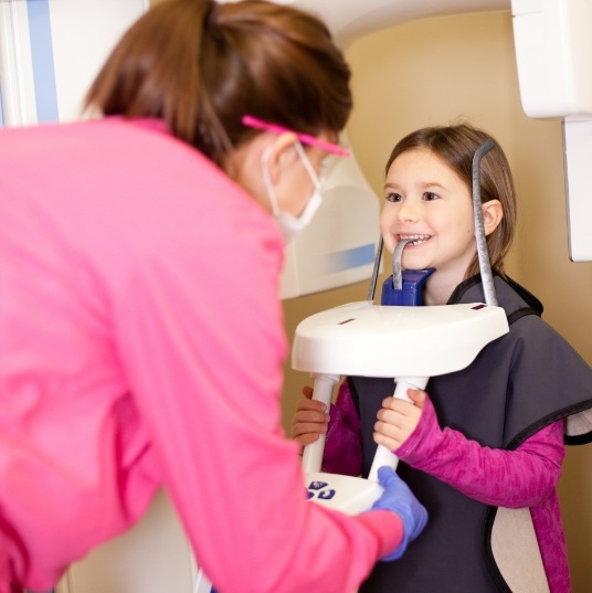 Dental team member helping young girl receive dental scan