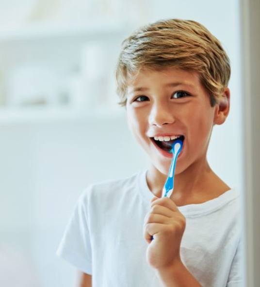 Boy brushing his teeth in front of mirror