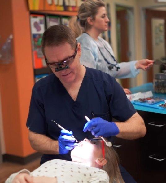 Doctor Dean performing pediatric dental exam on young girl
