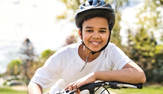 Smiling young boy with helmet riding bicycle