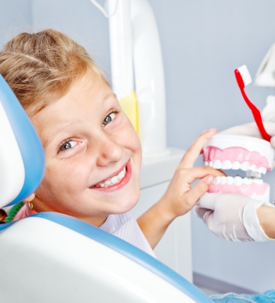 Young boy holding a model of teeth during pediatric preventive dentistry visit in Independence