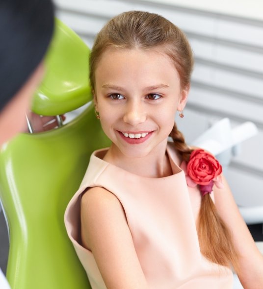 Little girl with braid smiling at dentist during dental checkup for kids